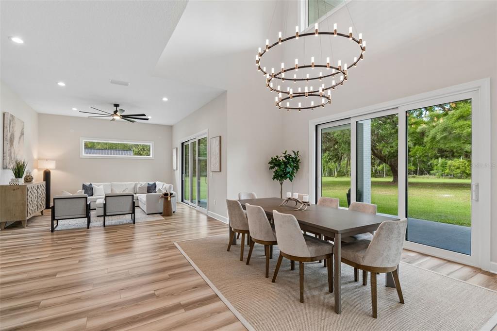 13711 Lussier Lane Spring Hill, FL 34610 - Photo 8 of 88 a dining room with wooden floor a chandelier a glass table and chairs