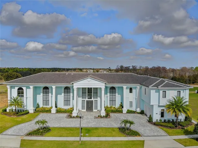 a front view of a house with swimming pool and red chairs