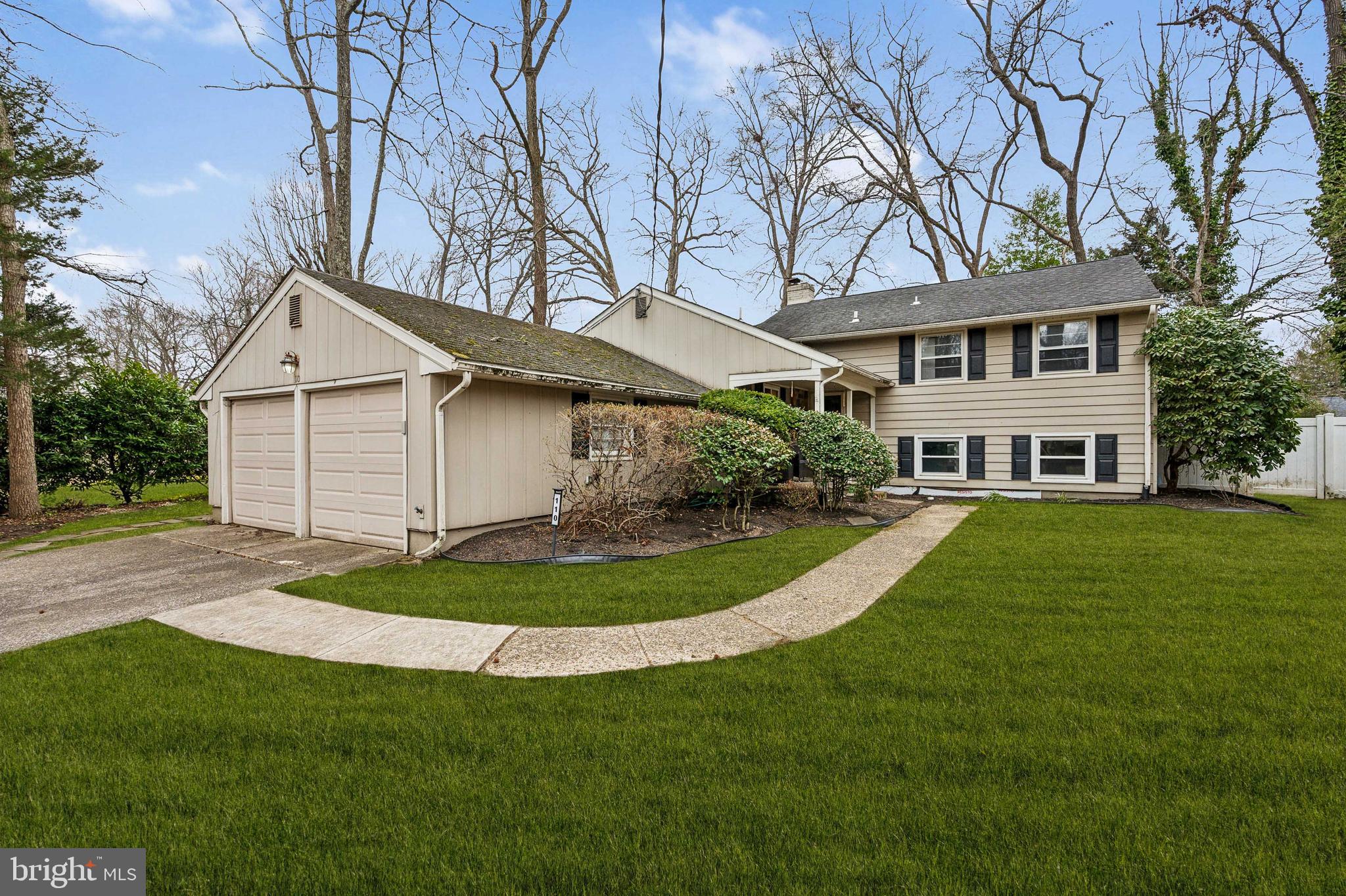 a front view of a house with a garden and trees