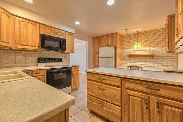 a kitchen with kitchen island granite countertop a sink appliances cabinets and a counter top space