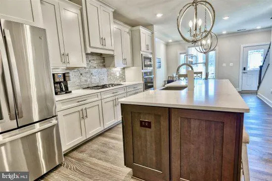 a kitchen with stainless steel appliances a sink a stove a refrigerator cabinets and wooden floor