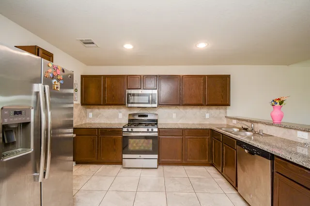 a kitchen with stainless steel appliances granite countertop a sink stove and refrigerator
