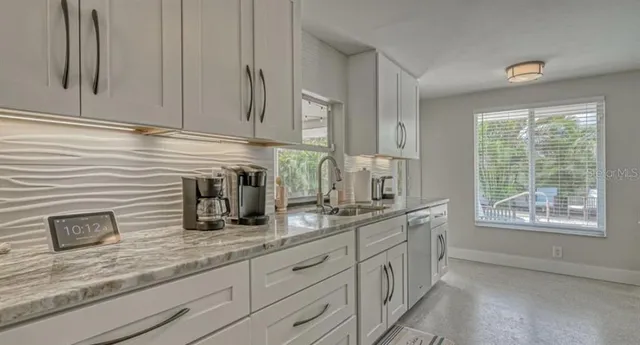 a kitchen with stainless steel appliances granite countertop white cabinets and window