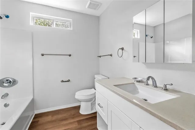 a view of an empty room with wooden floor and closet