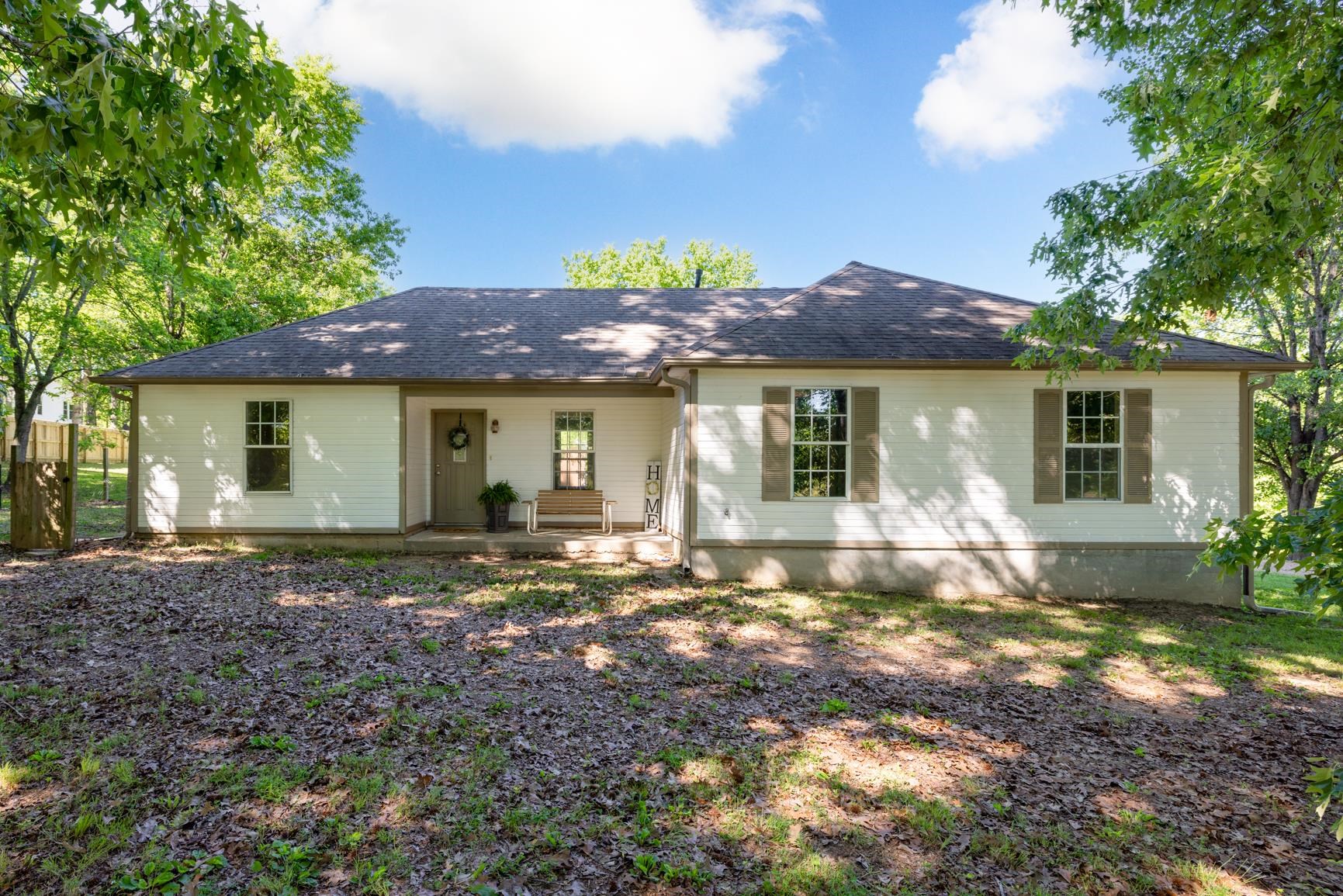 Ranch-style residence featuring white siding, a dark shingle roof, and a covered entry