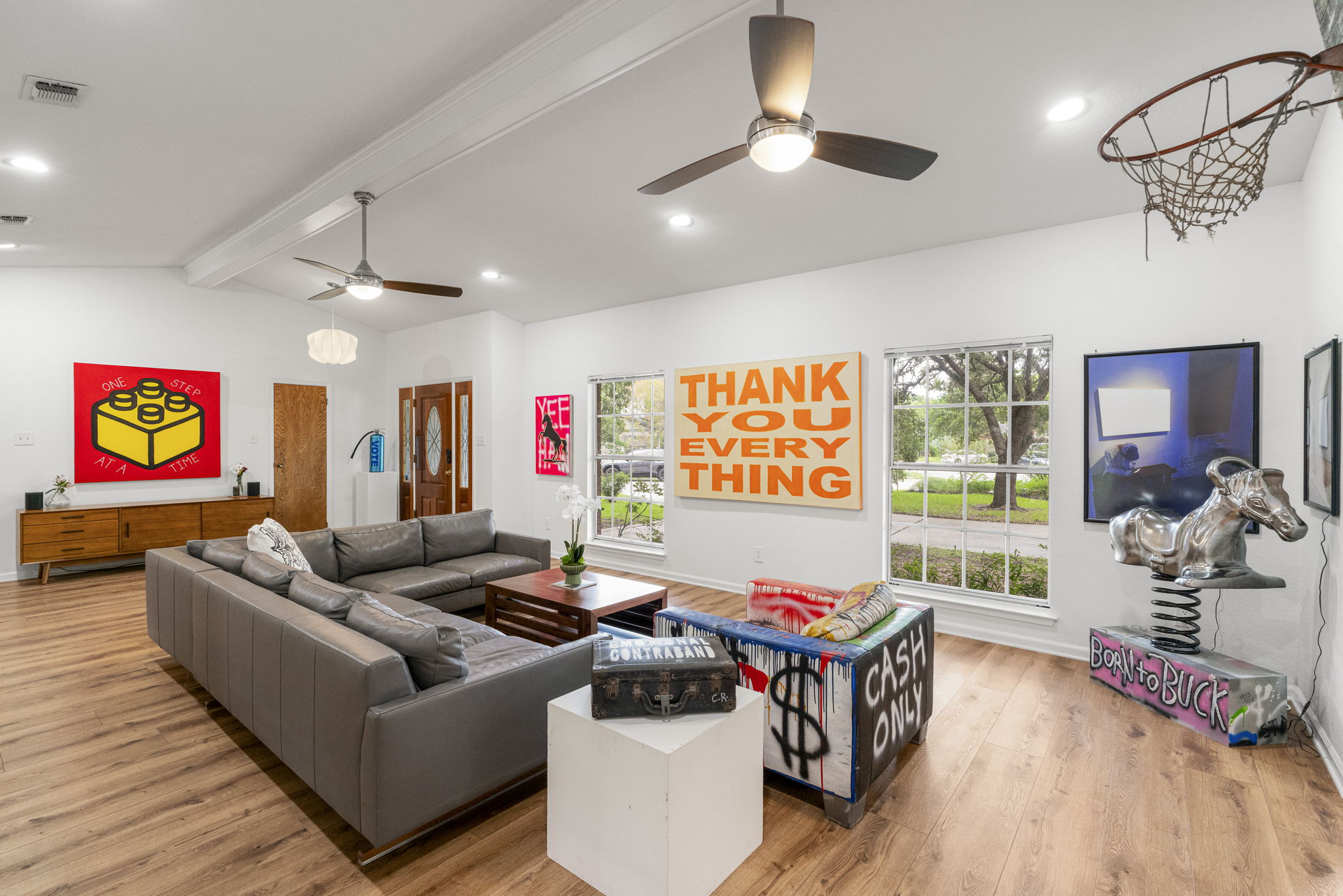 An inviting gathering space features warm wood flooring and abundant natural light from multiple large windows.