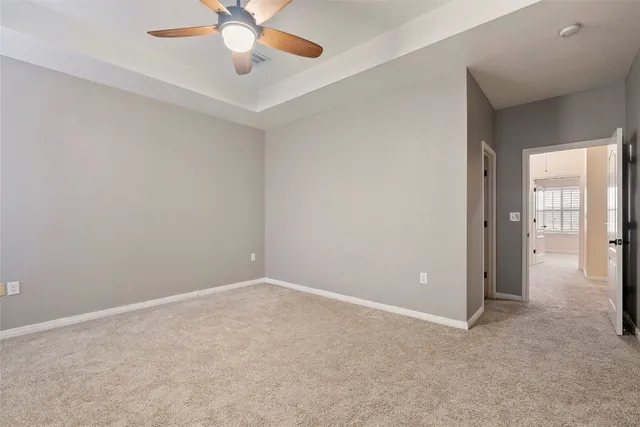 an empty room with chandelier fan and windows