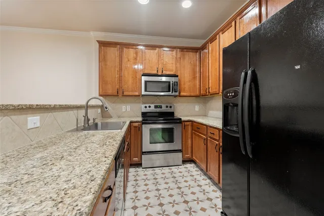 a kitchen with granite countertop a stove top oven microwave and refrigerator