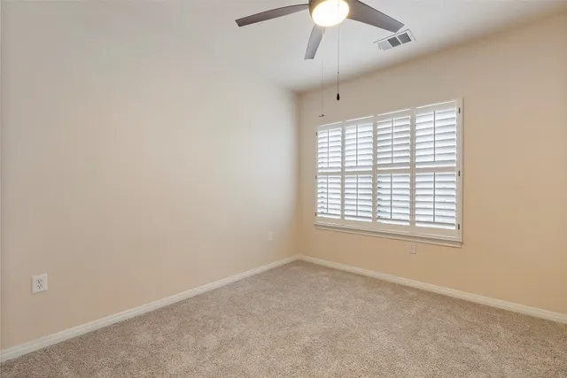 an empty room with a window and a ceiling fan