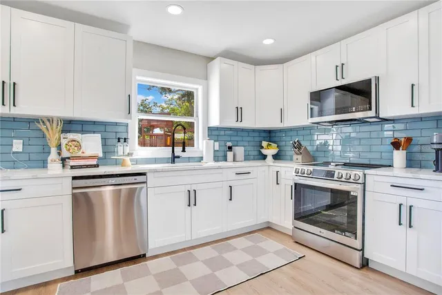 a kitchen with stainless steel appliances granite countertop white cabinets a sink and a stove
