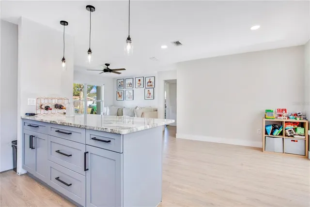 a view of a kitchen with stainless steel appliances granite countertop a sink stove and white cabinets with wooden floor