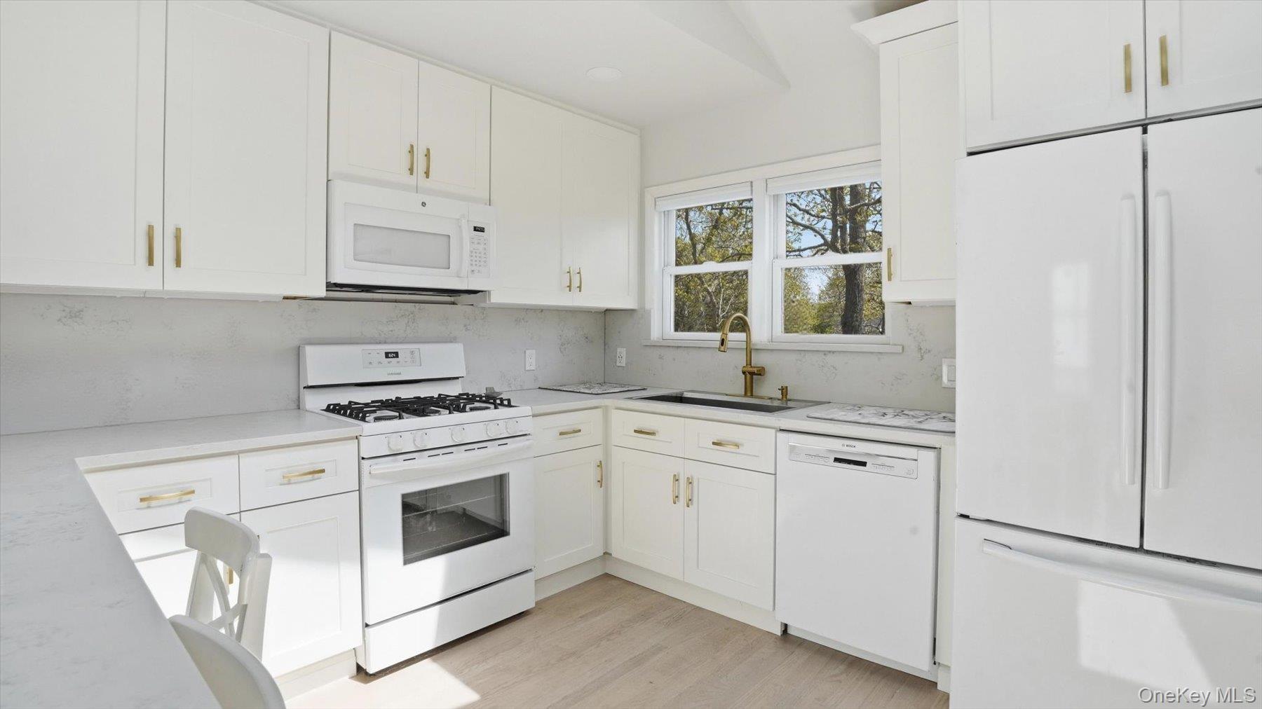 32 Red Creek Road Hampton Bays, NY 11946 - Photo 9 of 18 a kitchen with granite countertop white cabinets and white appliances