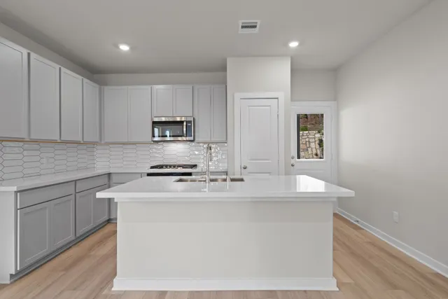a kitchen with kitchen island a sink a stove a microwave and cabinets
