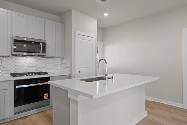 a kitchen with stainless steel appliances a stove a microwave a sink and cabinets