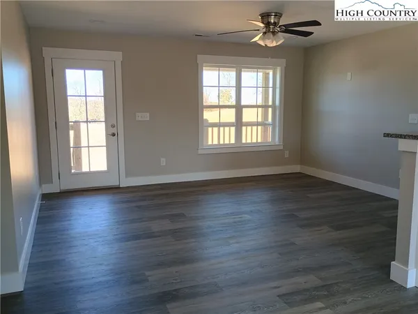 an empty room with wooden floor windows and a ceiling fan