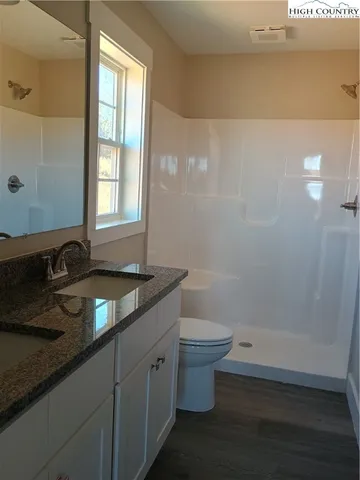 a bathroom with a granite countertop sink a toilet and shower