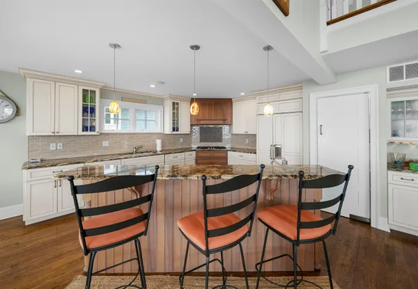 a kitchen with stainless steel appliances granite countertop a stove top oven a sink a dining table and chairs with wooden floor