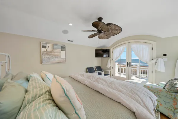 a bedroom with a bed ceiling fan and a large window
