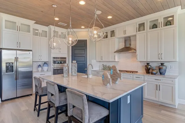 a kitchen with granite countertop a table chairs stainless steel appliances and cabinets