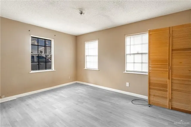 an empty room with wooden floor and windows