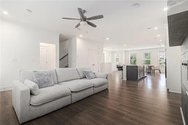 a living room with furniture kitchen view and a wooden floor