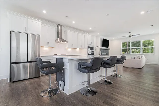 a kitchen with stainless steel appliances granite countertop a refrigerator a stove a sink a dining table and chairs with wooden floor