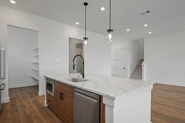 a kitchen with a sink a chandelier stainless steel appliances and cabinets