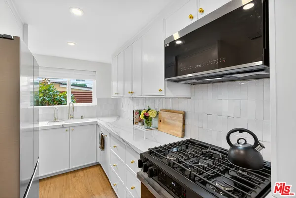 a kitchen with stainless steel appliances granite countertop a sink stove and microwave