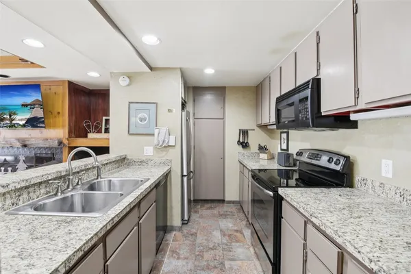 a kitchen with stainless steel appliances granite countertop a sink a stove and a refrigerator