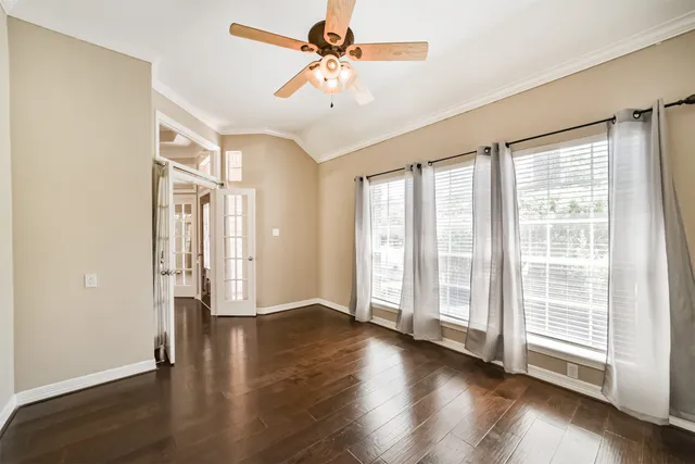 a view of an empty room with a window and wooden floor