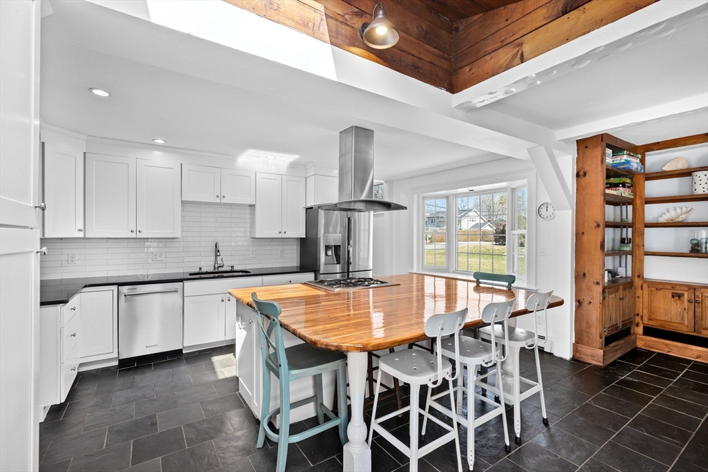 59 Gannett Road Scituate, MA 02066 - Photo 2 of 40 a kitchen with stainless steel appliances granite countertop a stove top oven a sink a dining table and chairs with white cabinets