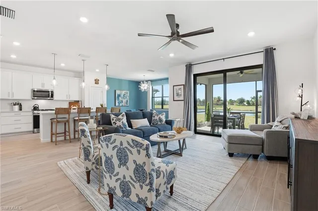 a living room with furniture kitchen area and a large window