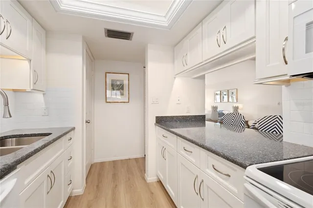 a kitchen with granite countertop a sink stove and cabinets