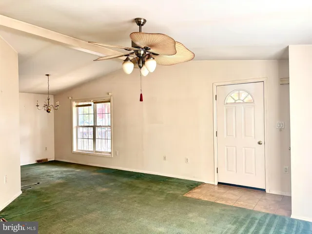 a view of a livingroom with a chandelier fan and windows
