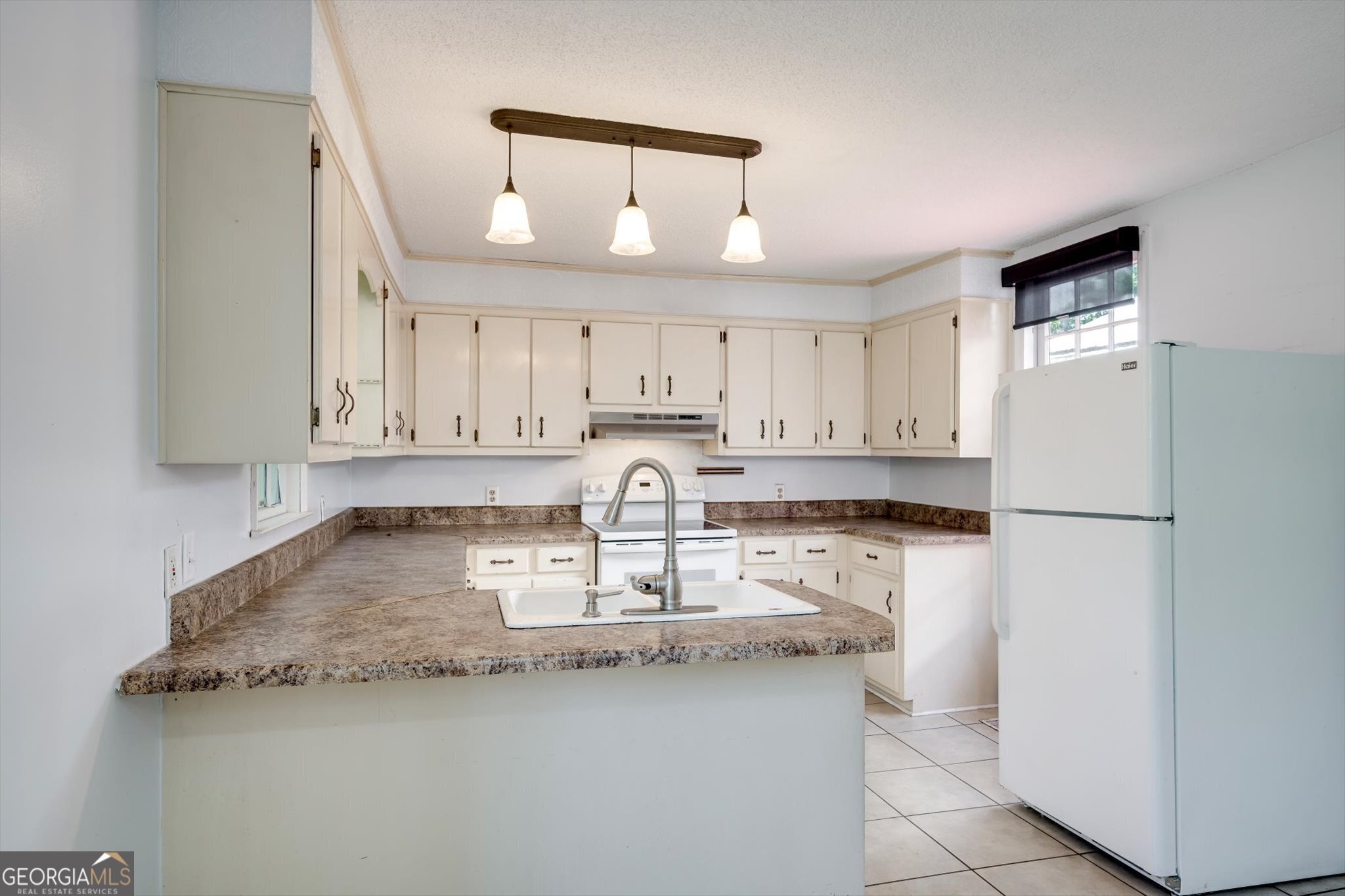 314 White Oak Street Thomson, GA 30824 - Photo 6 of 14 a kitchen with granite countertop a refrigerator a sink a stove a microwave and white cabinets