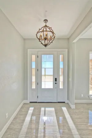 a view of an empty room with window and chandelier fan