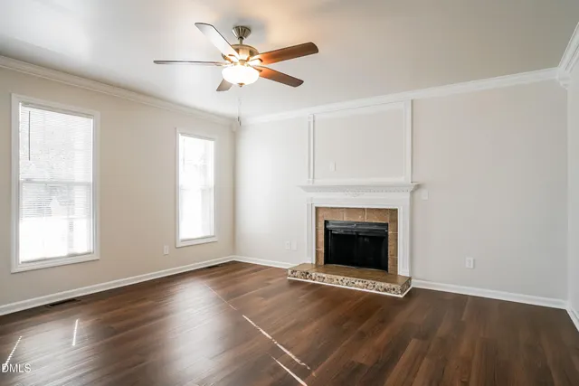 an empty room with wooden floor fireplace and windows