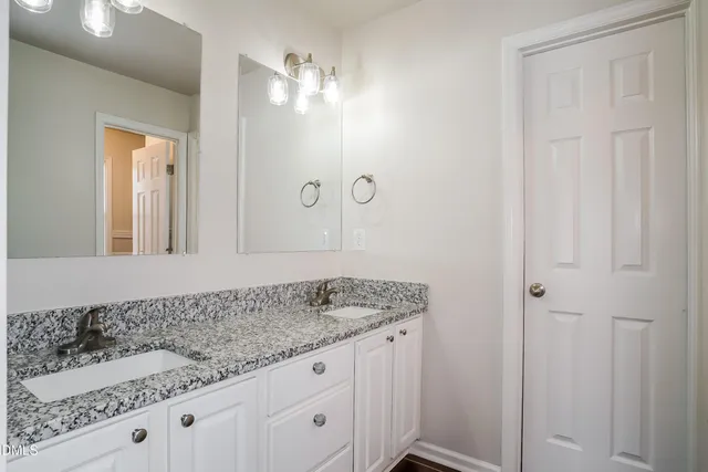 a bathroom with a granite countertop sink and white cabinets