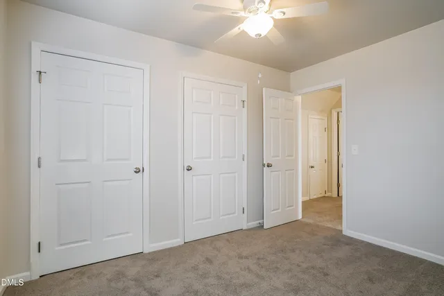 a view of an empty room and chandelier fan