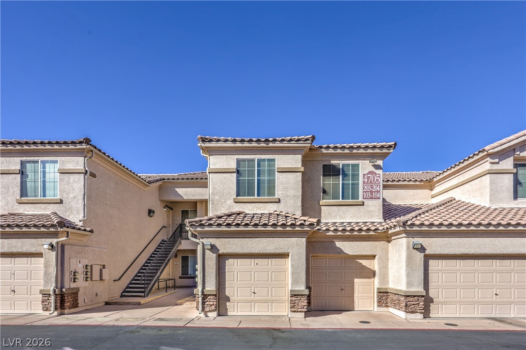 4705 Apulia Drive, Unit 203 North Las Vegas, NV 89084 - Photo 2 of 39 A cream-colored multi-story building features private garages and exterior stair access to upper units.