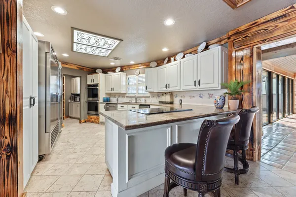 a kitchen with stainless steel appliances granite countertop a table chairs cabinets and wooden floor