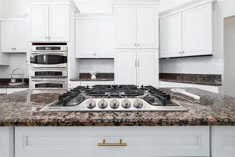a kitchen with stainless steel appliances granite countertop a stove and a white cabinets