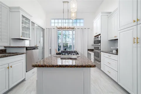 a kitchen with kitchen island granite countertop a stove and a white cabinets