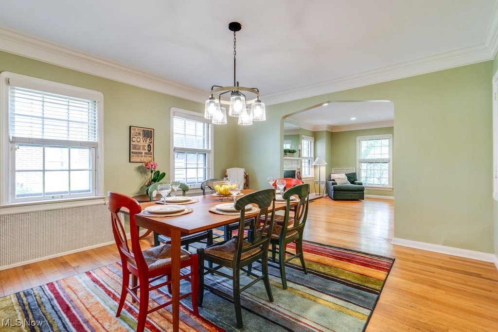 2500 Eaton Road Cleveland, OH 44118 - Photo 23 of 50 Dining room with arched walkways, light wood finished floors, ornamental molding, a chandelier, and baseboards