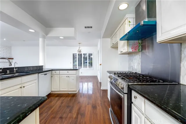 a kitchen with granite countertop a sink a stove and wooden cabinets