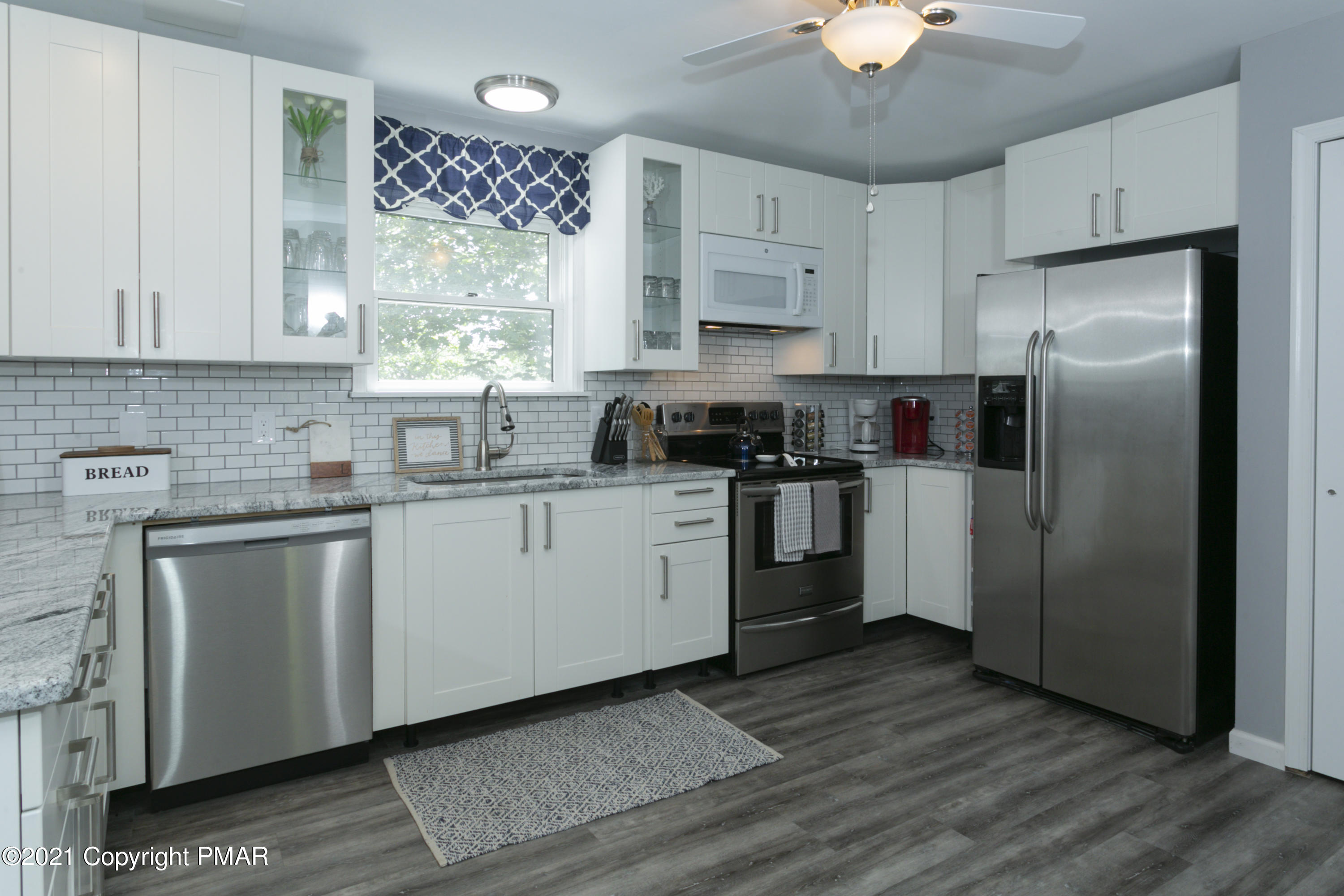 2155 Lancaster Drive Bushkill, PA 18324 - Photo 9 of 57 a kitchen with a refrigerator a sink dishwasher a stove and white cabinets with wooden floor
