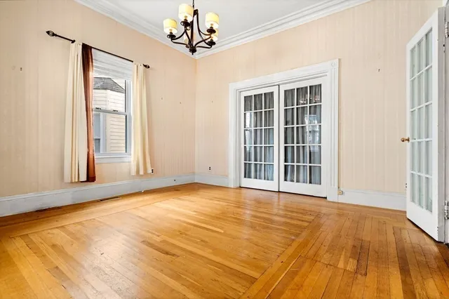 a view of an empty room with a window and wooden floor