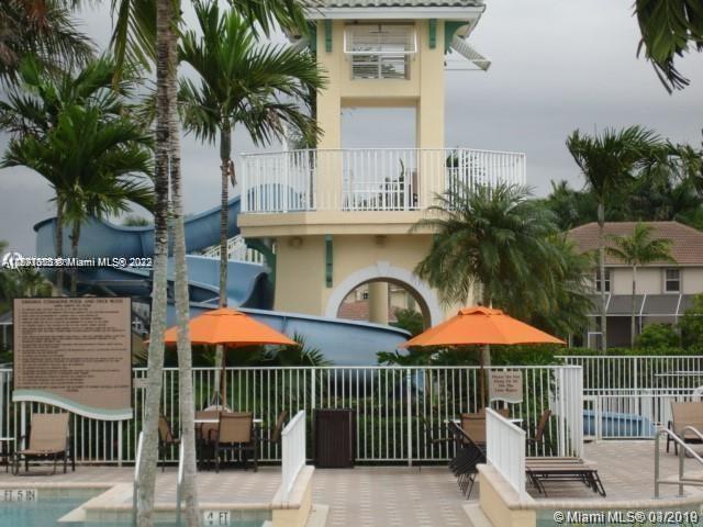 Savanna Weston, FL 33327 - Photo 23 of 24 a view of a patio with a table and chairs under an umbrella with palm trees
