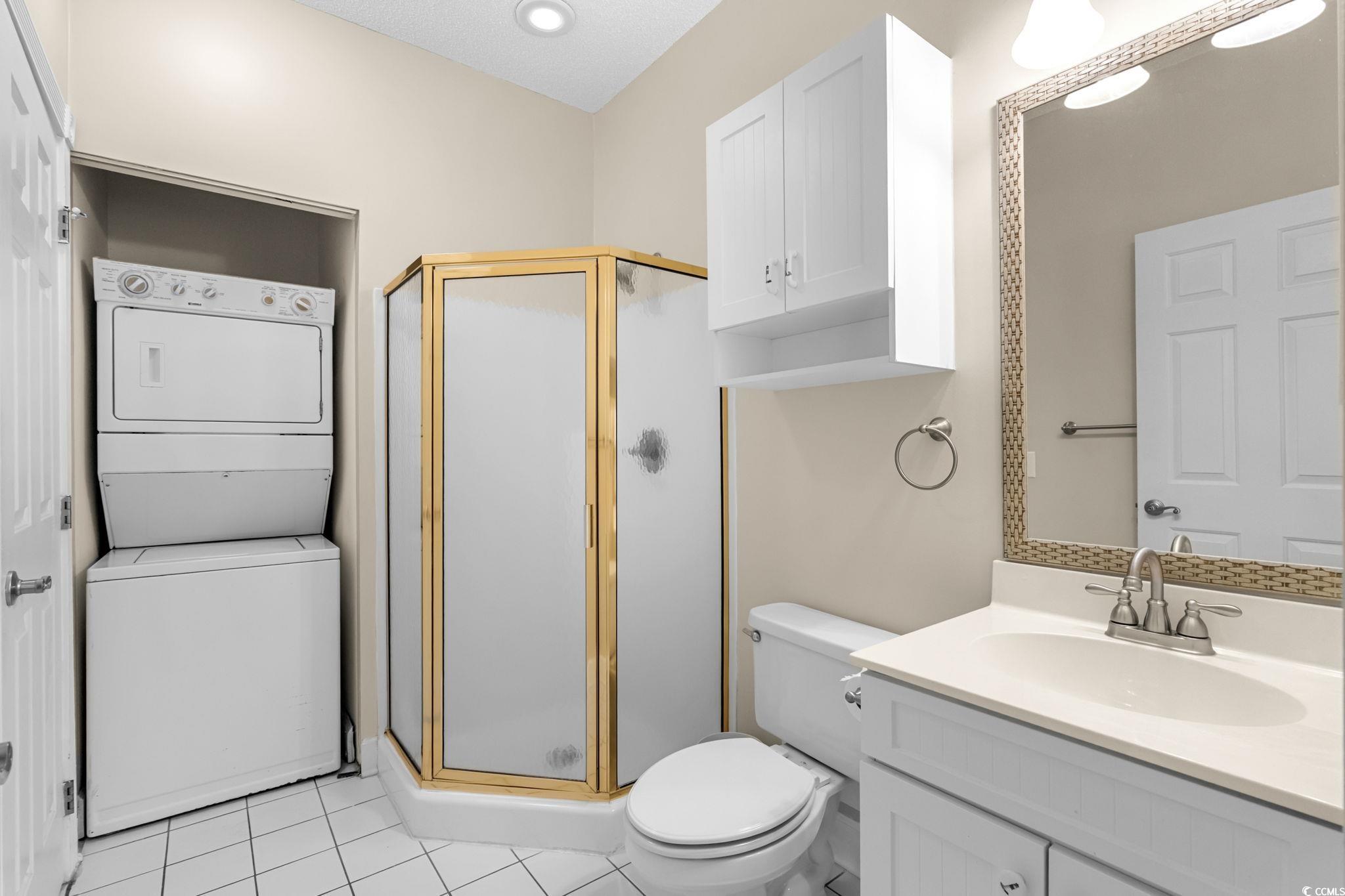 4815 Orchid Way, Unit 302 Myrtle Beach, SC 29577 - Photo 16 of 26 Bathroom featuring a shower stall, stacked washer and clothes dryer, vanity, and light tile patterned flooring