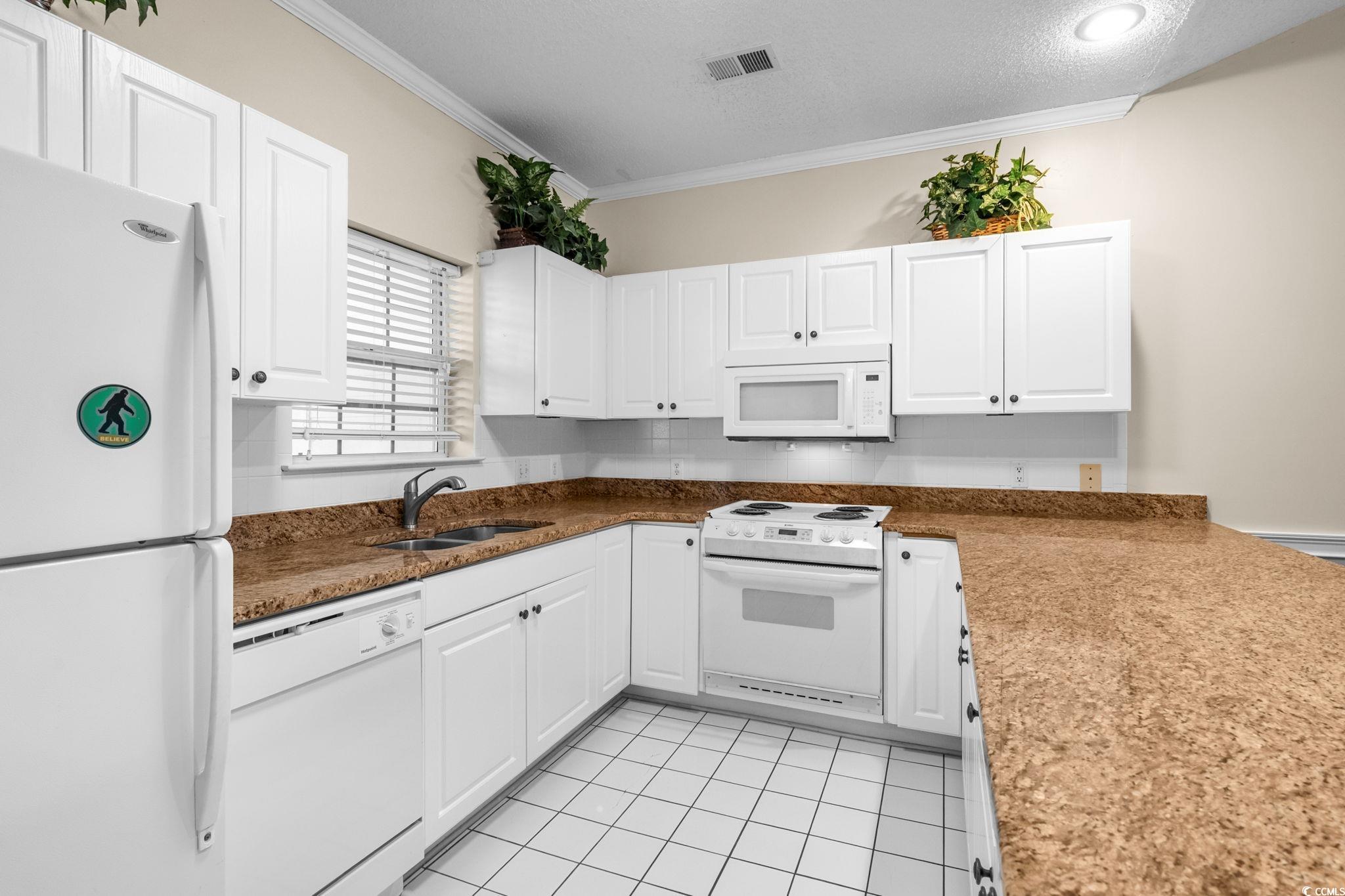 4815 Orchid Way, Unit 302 Myrtle Beach, SC 29577 - Photo 5 of 26 Kitchen with white appliances, white cabinets, a textured ceiling, light tile patterned flooring, and dark stone counters